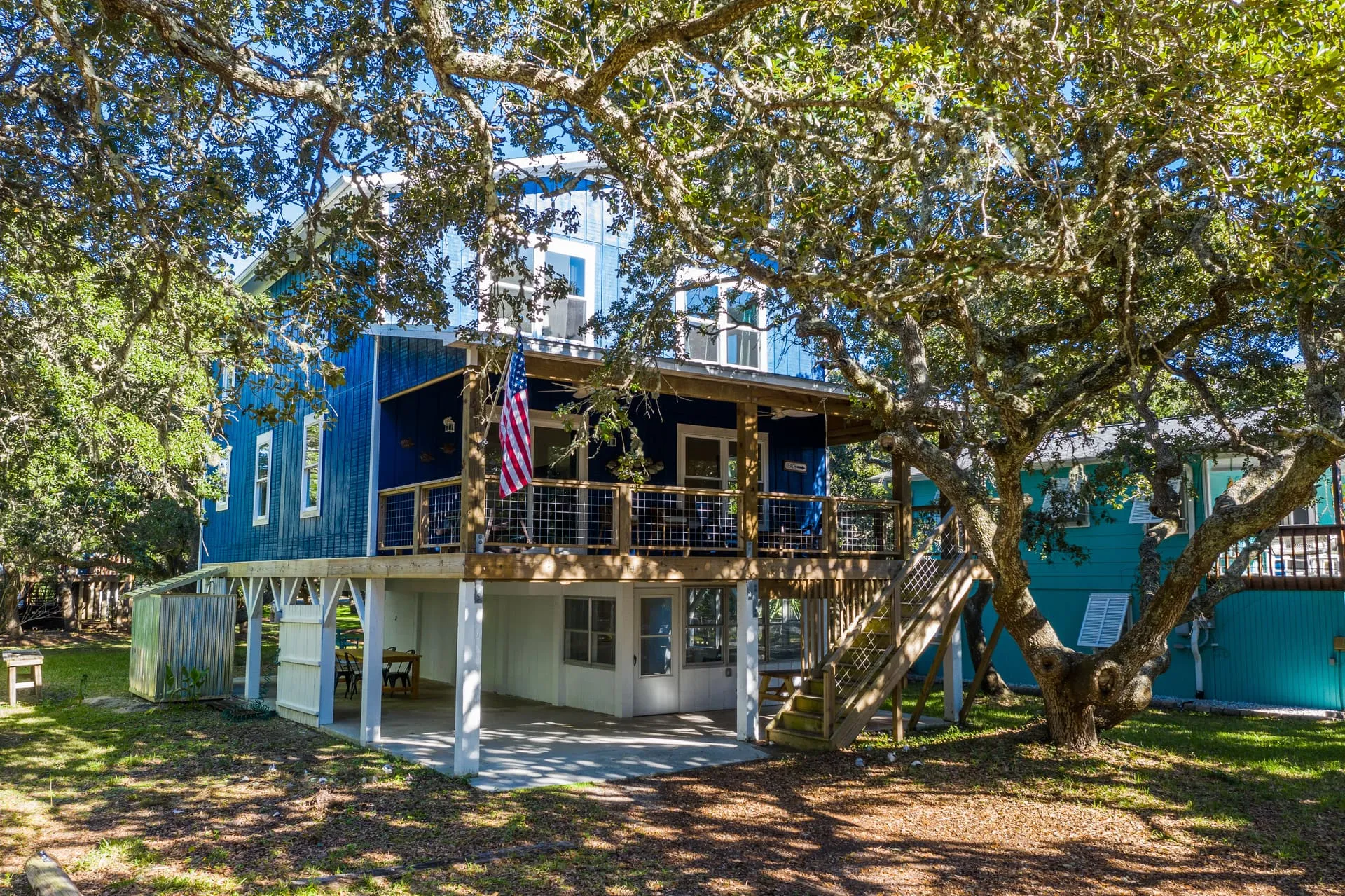 Front of the house with the flag and upper deck under the oak canopy