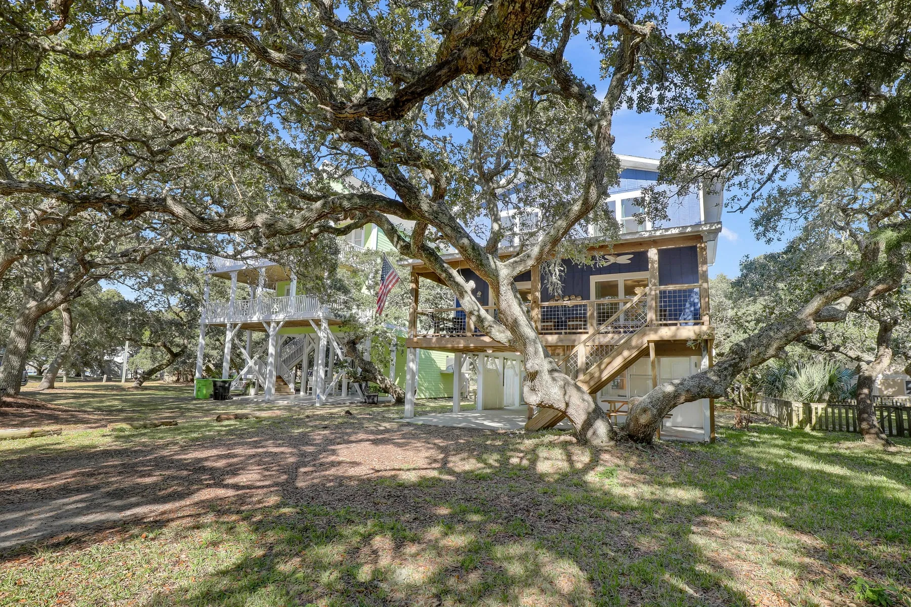 The blue Sound to Sea beach house framed by a live oak tree on Topsail Island